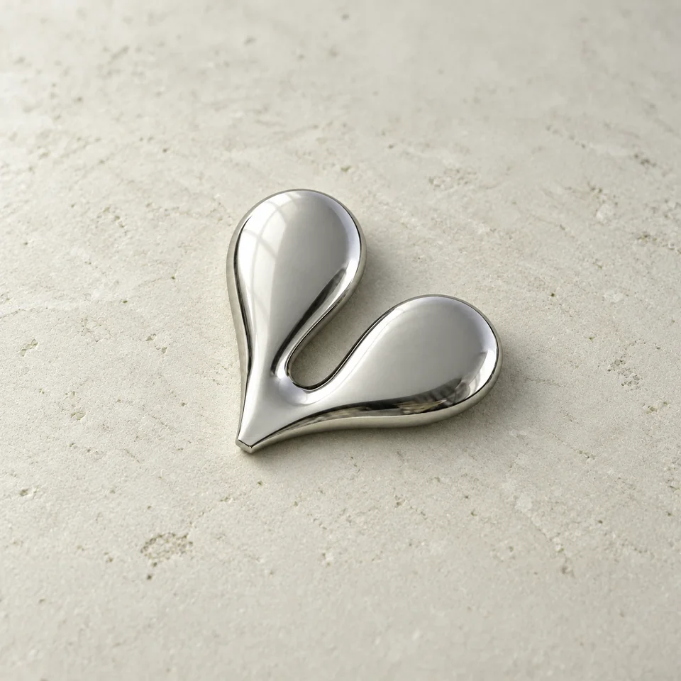Alessi: polished steel heart-shaped object on pale stone