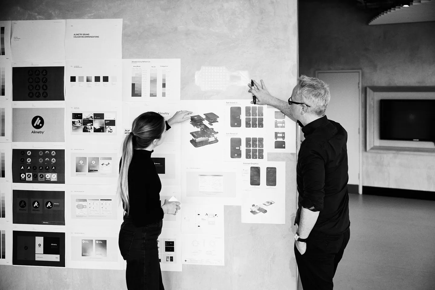 Jim Hannon-Tan reviewing design work pinned to the studio wall